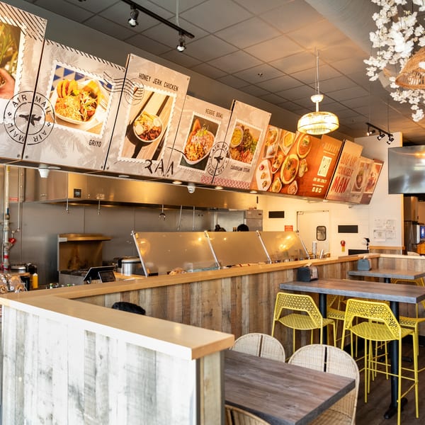Manjay Restaurant's interior shows a service counter with menu boards above and dining tables with yellow chairs.