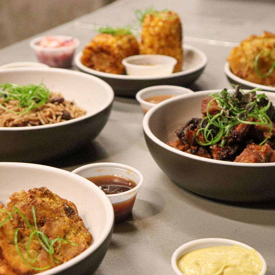 A variety of Caribbean dishes from Manjay Restaurant, including rice, meat, and fried plantains.