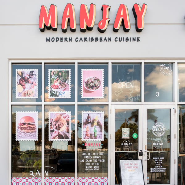 Manjay Restaurant storefront with a red sign, food pictures, and business hours on the windows.